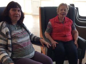 Resident and carer sitting in chairs smiling