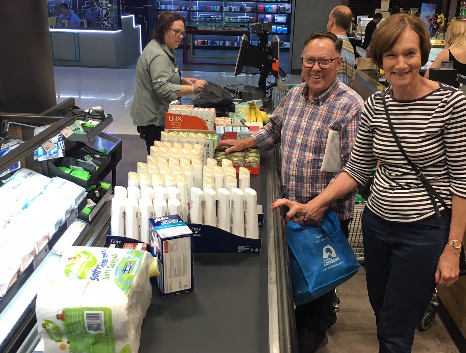 Two volunteers standing at Woolies check out with lots of goods